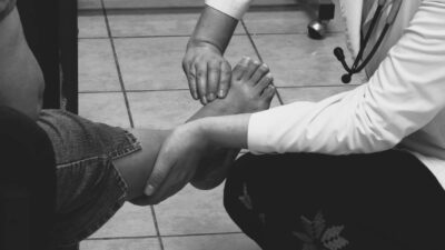 Doctor examines a patient's foot during a medical consultation in a clinic setting.