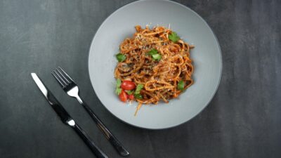 a plate of pasta with tomatoes and basil