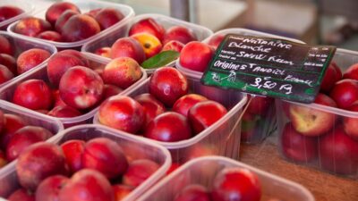 a table topped with plastic containers filled with red apples