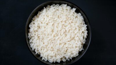 A bowl filled with freshly cooked white rice, shot from above against a dark background for contrast.