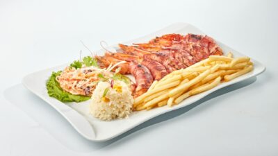 Seafood platter featuring grilled shrimp, fries, and rice on a white plate.