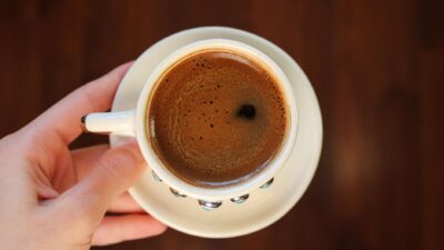 Top view of a freshly brewed espresso cup held by hand, perfect for coffee enthusiasts.