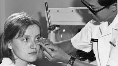 Doctor examines a woman's eye with equipment.