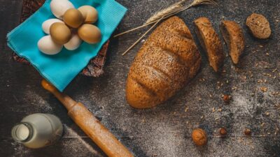a loaf of bread, eggs and a rolling pin on a table
