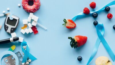 Diabetes awareness theme with fruits, sugar cubes, and glucose meter on blue background.