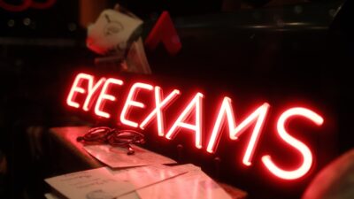 Red neon sign reading "eye exams"