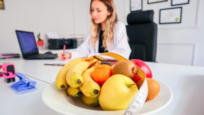 a woman sitting at a desk with a bowl of fruit