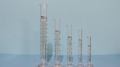 A variety of graduated cylinders in different sizes on a blue surface, ideal lab equipment image.