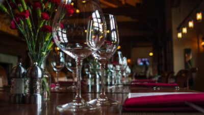 two empty wine glasses beside red flower centerpiece