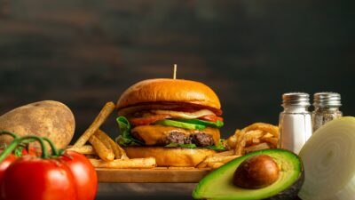a hamburger, french fries, avocado, tomato, onion, and salt