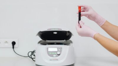 Medical professional handling blood sample in a centrifuge for laboratory testing.