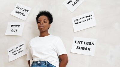 African American woman stands near motivational health slogans on the wall, promoting a positive lifestyle.
