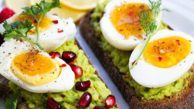 Savor this delicious avocado toast topped with soft-boiled eggs and garnished with pomegranate seeds.
