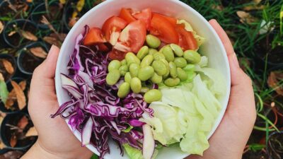 A vibrant bowl of fresh garden salad featuring tomatoes, edamame, and cabbage. Perfect for healthy dining.