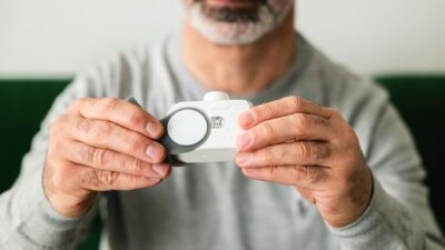 A close-up of a man using a handheld air quality analyzer, focusing on health and technology.