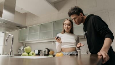 A couple discusses diabetes management while using a glucometer in a modern kitchen setting.