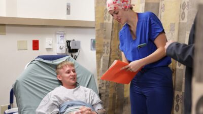 Nurse talking to patient in hospital bed.