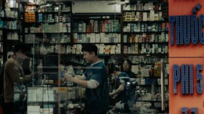 People inside a well-stocked pharmacy with glass doors.