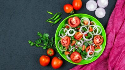 A vibrant vegetable salad featuring tomatoes, onions, and greens in a colorful setting.