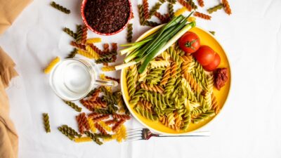 a plate of pasta with green beans and tomatoes