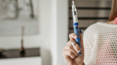 Woman holding an insulin pen, showcasing healthcare and diabetes management in a modern setting.