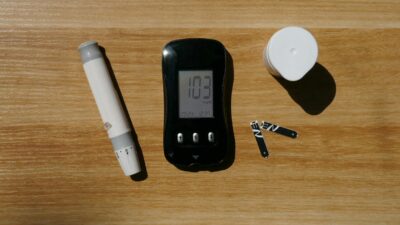 A diabetes testing kit with glucose meter, lancet pen, and test strips on a wooden surface.