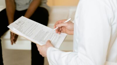 Healthcare professional reviews medical form during patient consultation in a clinic setting.