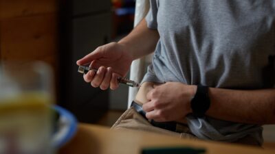 a person injecting insulin into stomach for diabetes management