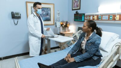 A medical professional conducts a check-up with a patient in a hospital setting.