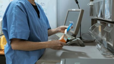Healthcare worker in scrubs organizing medication in a medical facility.