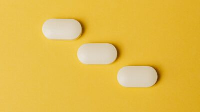 Top view closeup composition of medical white pills placed diagonally on vivid bright yellow background