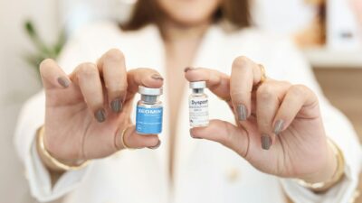 A close-up of a woman holding Xeomin and Dysport vials, showcasing cosmetic treatment options.