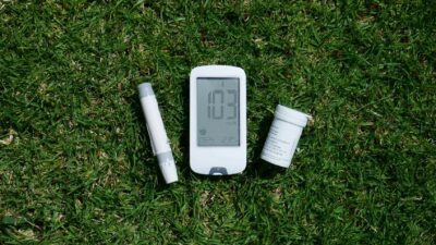 Diabetes management tools including glucose meter and test strips on grass, highlighting outdoor use.