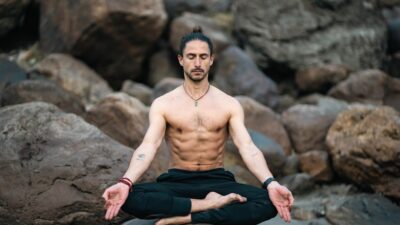 a man sitting on a rock doing yoga