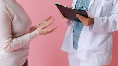 Close-up of a patient consulting a doctor with a clipboard in a medical setting.