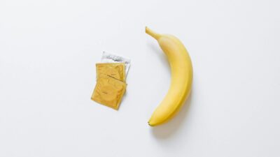 A yellow banana next to packaged condoms on a white surface, symbolizing safe sex.
