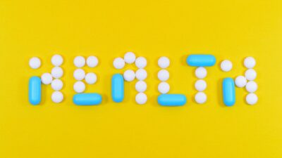 Pills spelling 'health' on a vibrant yellow background, symbolizing wellness.