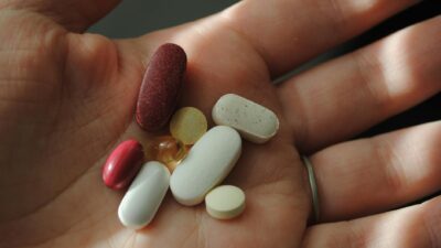 A close-up image of assorted pills and vitamins being held in a hand.