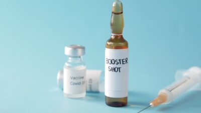 a bottle of booster shot next to a syringe