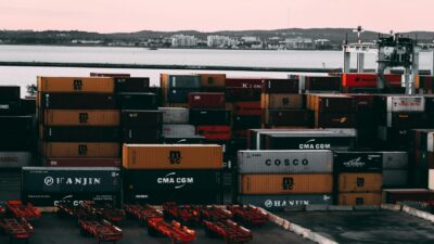 A bustling container yard at a seaport with shipping containers stacked and ready for transport at twilight.
