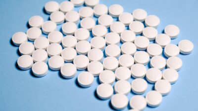 Close-up of white pills on a blue surface representing healthcare and medication.