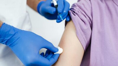 Close-up of a health professional administering a vaccine injection to a patient's arm.