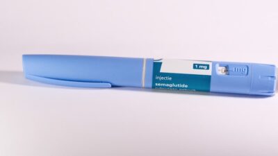 A blue insulin pen rests on a white surface.