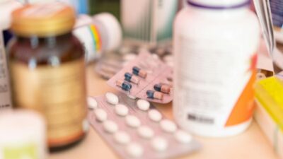 Close-up shot of various pharmaceutical pills, capsules, and medication bottles on a table.