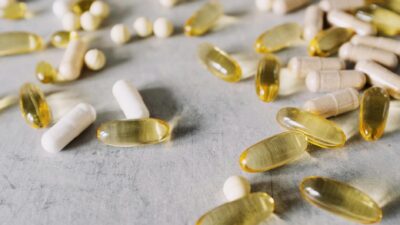 Close-up of assorted capsules and pills spread across a gray surface, capturing diverse pharmaceutical forms.