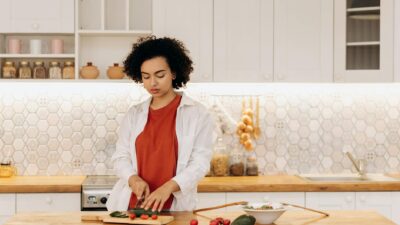 A woman slicing vegetables in a modern kitchen, showcasing healthy cooking and lifestyle.