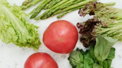 Top view of fresh asparagus, lettuce, basil, and tomatoes, highlighting healthy and nutritious ingredients.