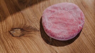Frozen red mochi placed on a wooden table, suitable for food photography needs.