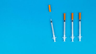 Four medical syringes with orange caps on a vivid blue background, ideal for healthcare or vaccination themes.