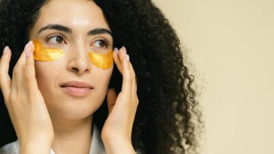 Close-up of a woman using gold under eye patches for skincare routine.